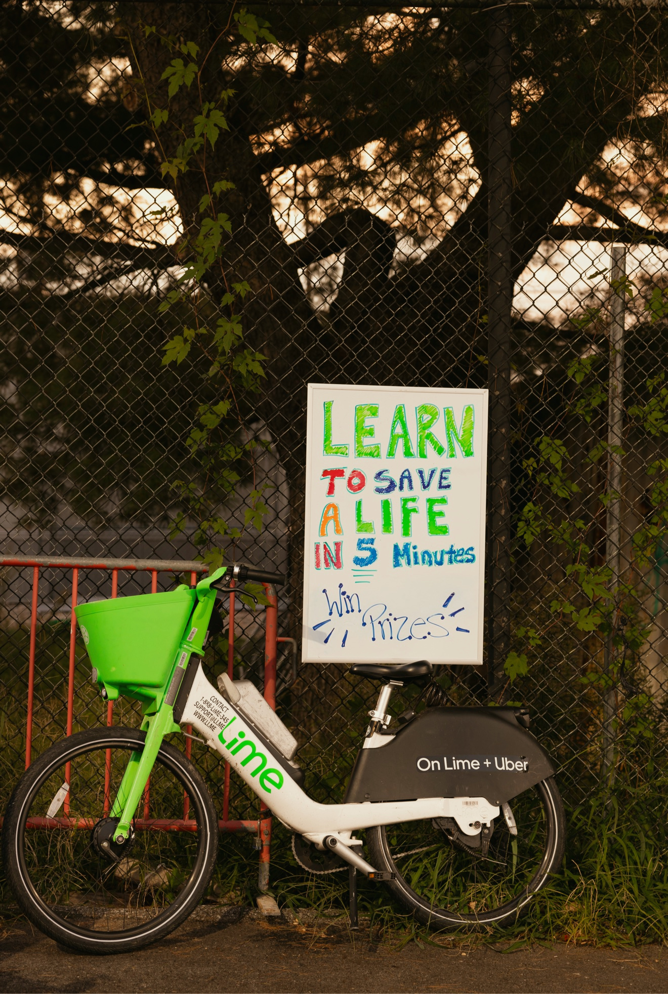 A Lime bike beside a Learn to Save a Life in 5 Minutes sign at a GoodWorks community event